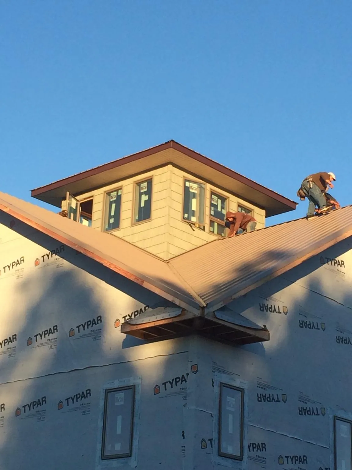 Roofers working around a rooftop cupola on a new metal roof at sunset — Roof Waterproofing in Bogalusa by Roofing Brothers
